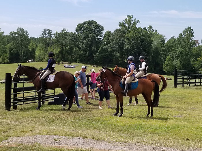 Win Green Cross country schooling facility, riders on horses standing in field.