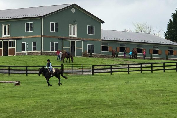 Win Green Cross country schooling in Northern Virginia, exterior of barn with riders and horses.